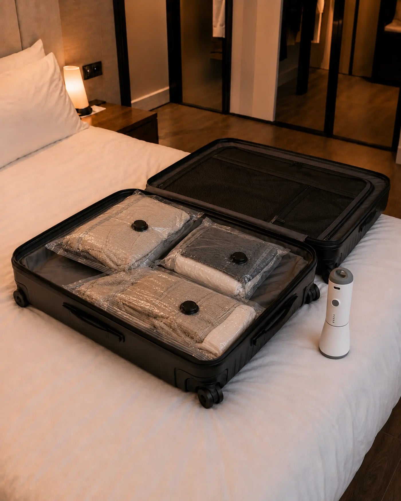 The same open black suitcase with the clothing arranged inside three clear compression bags and the SG-508 pump beside it.