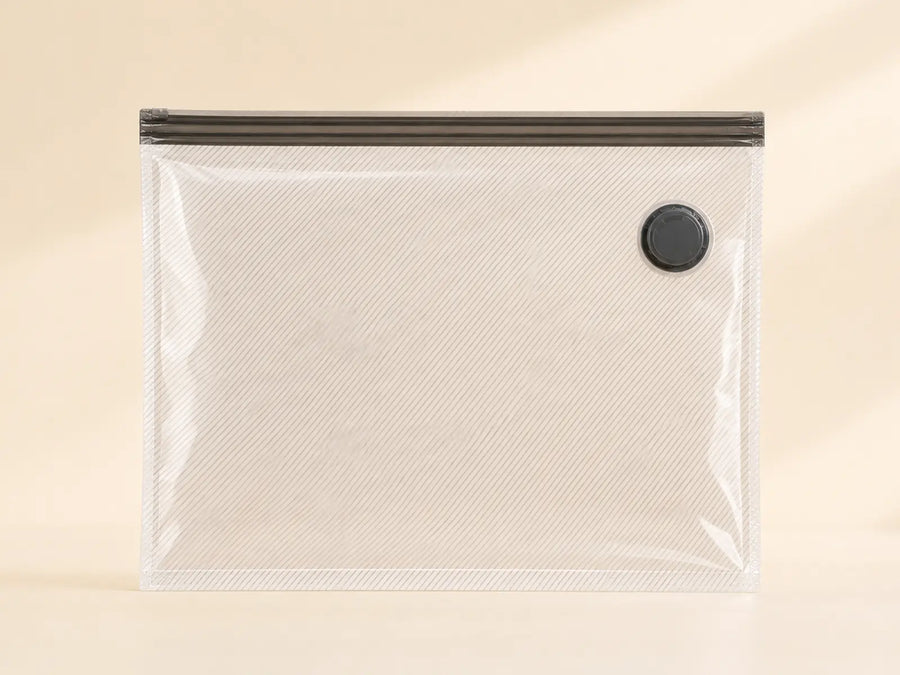 Clear ribbed 26-inch travel compression bag with a dark double-zip closure and black valve.
