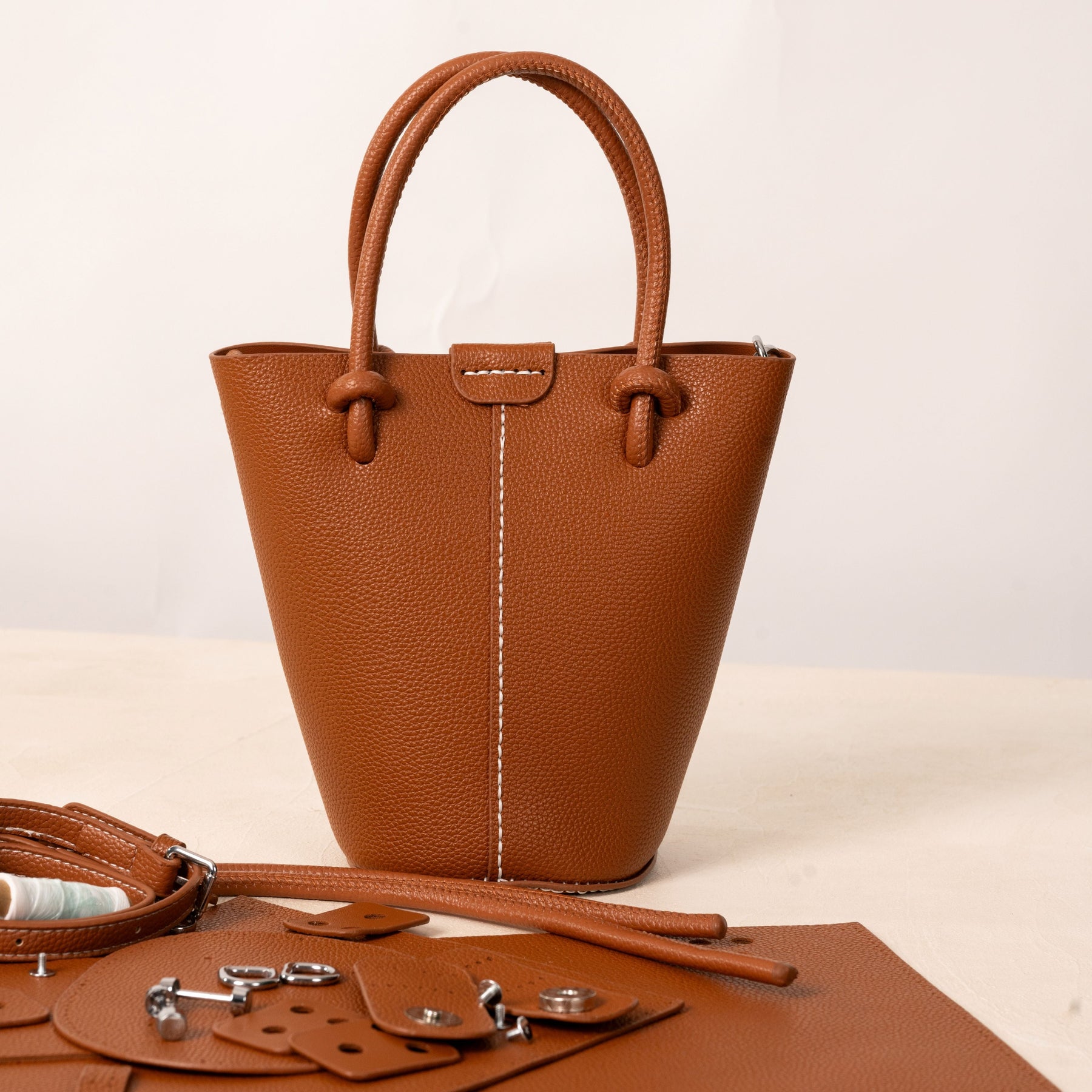Finished brown Aurea handbag beside its matching pieces and hardware