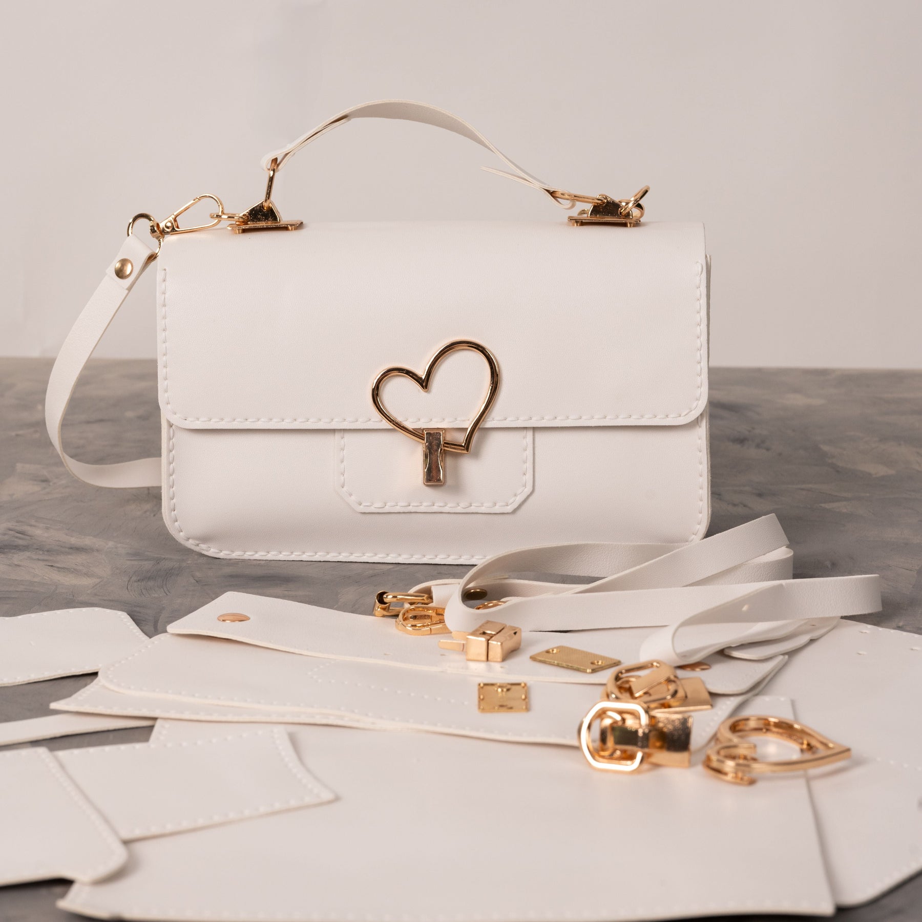 Finished white and blue Moytsa handbag beside matching pieces and gold hardware